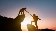 A photo of a climber helping another climber
